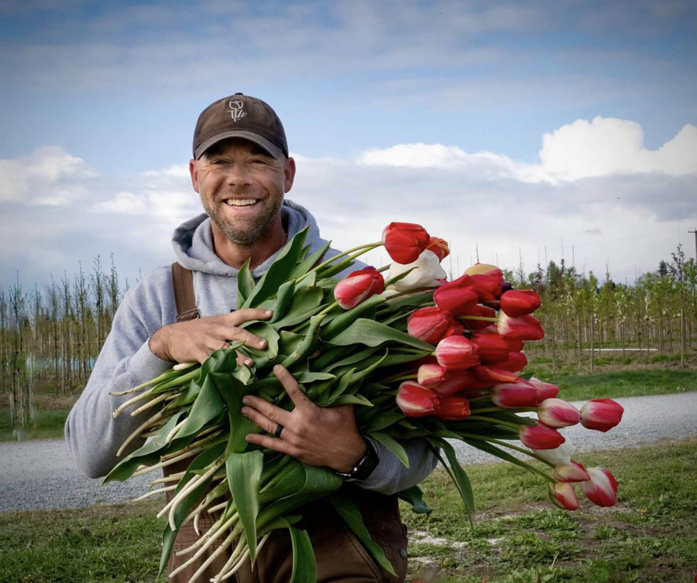 Andrew holding a bundle of red and pink tulips at Tulip Valley Farms