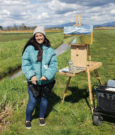 Artist at Tulip Valley Farms with an easel and painting of a landscape