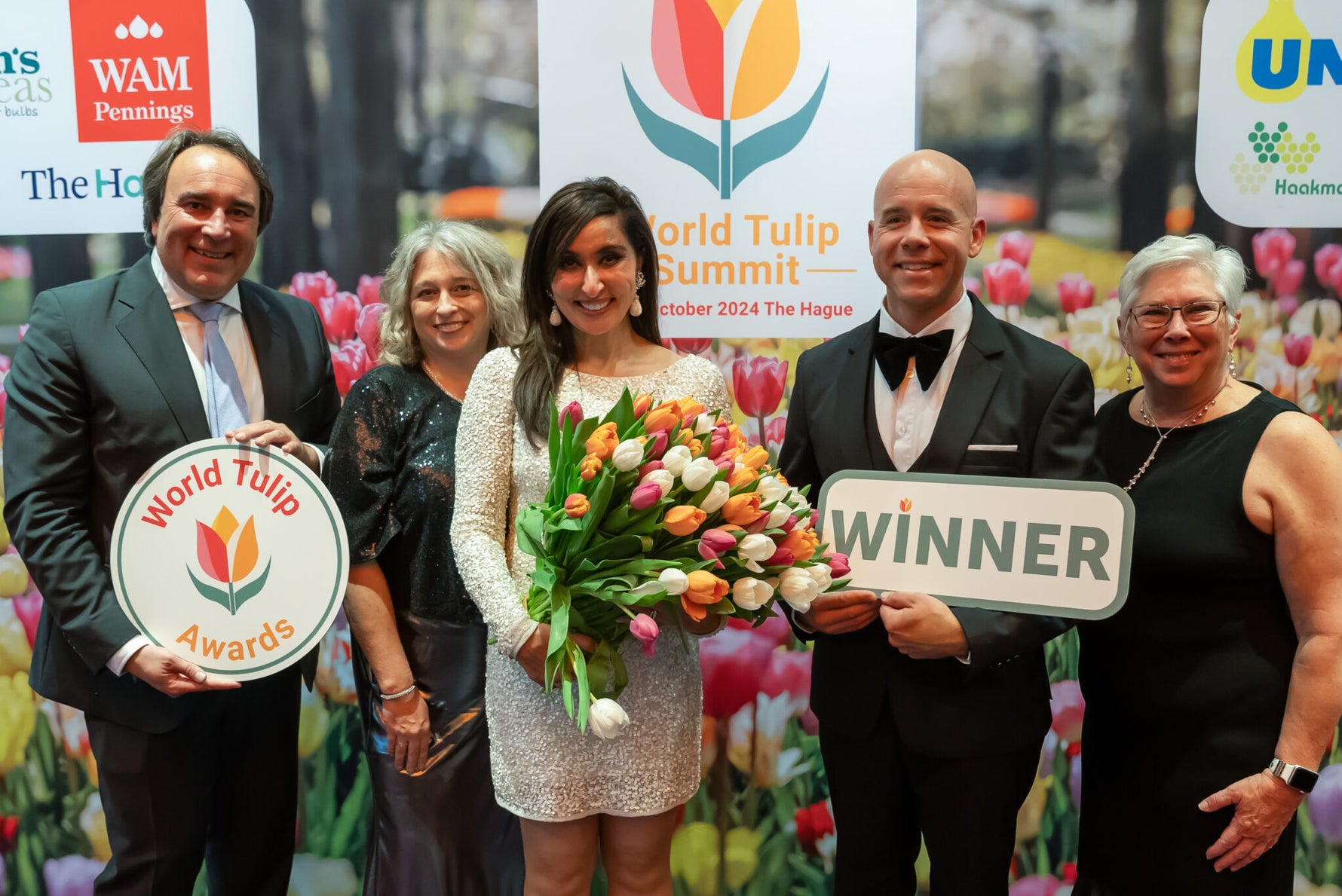 Group of people celebrating with World Tulip Awards and Winner signs, surrounded by tulips.